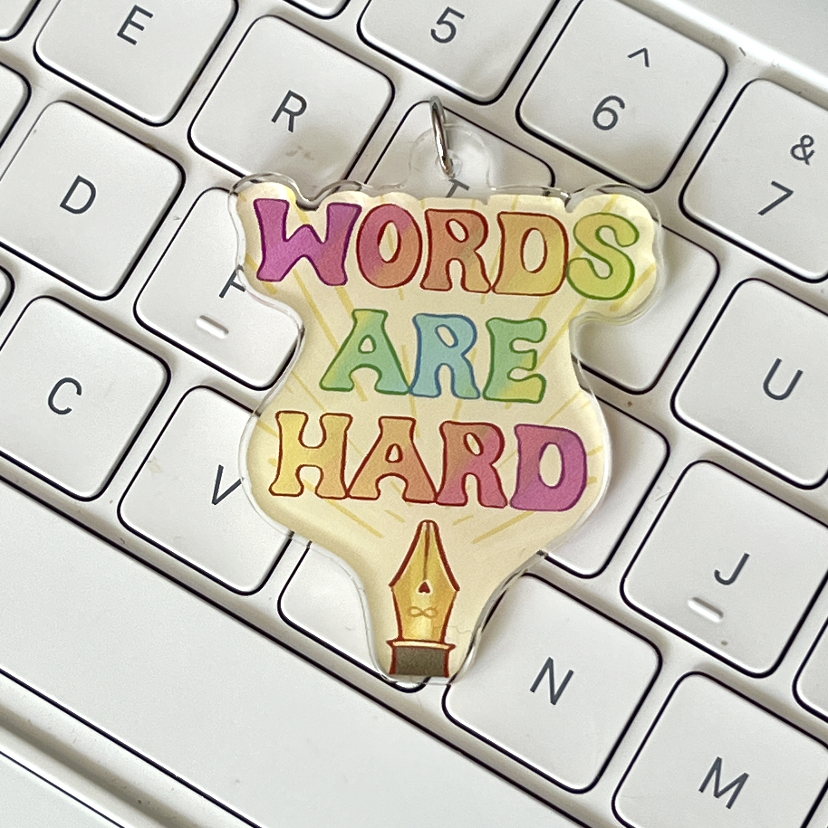 Keychain art designed by Amanda Vacharat with a fountain pen nib and the words ‘words are hard’